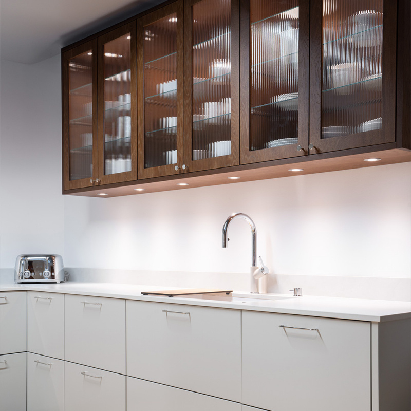 Kjøkkenhåndtak Spira i et lekkert kjøkken med overskap i mørkbeiset tre og beige kjøkkendører nederst